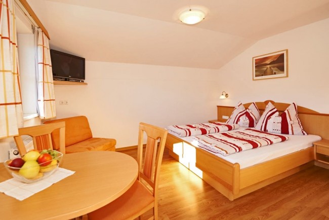 Schlafzimmer mit Doppelbett, Schrank, Tisch und Couche