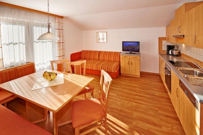 Wohnraum mit Küche, Esstisch und TV